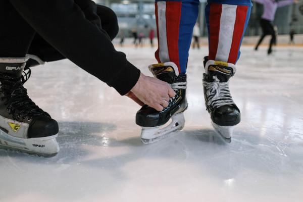 person tying another person's ice skates